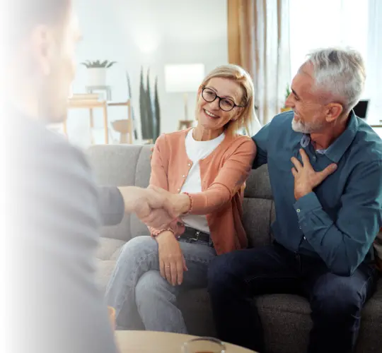 husband holds chest in mock surprise as wife agrees to giving all their money away with a handshake